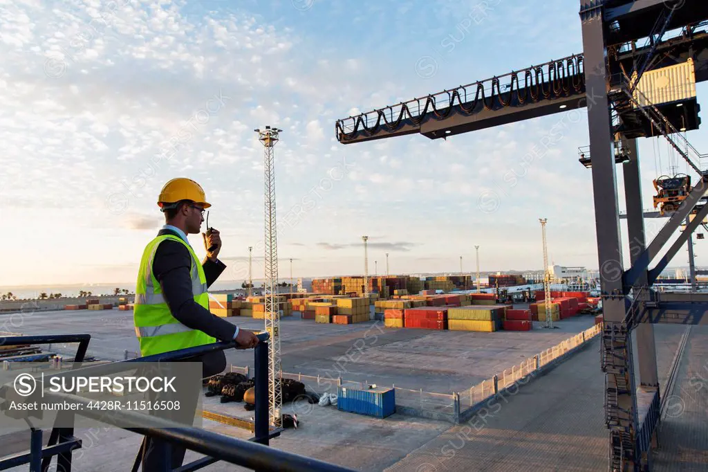Worker using walkie-talkie near crane