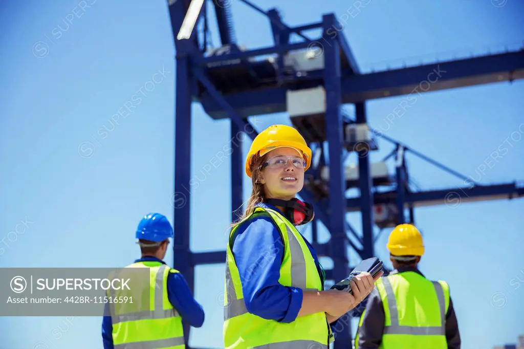 Low angle view of workers standing under cargo crane