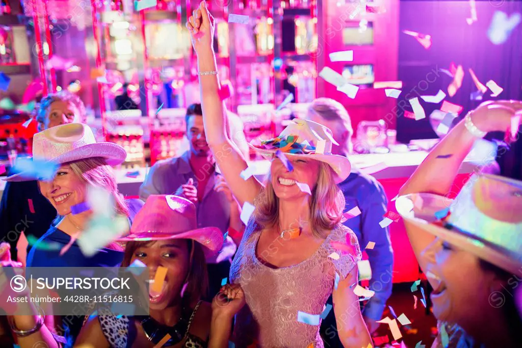 Confetti falling on women wearing cowboy hats dancing in nightclub
