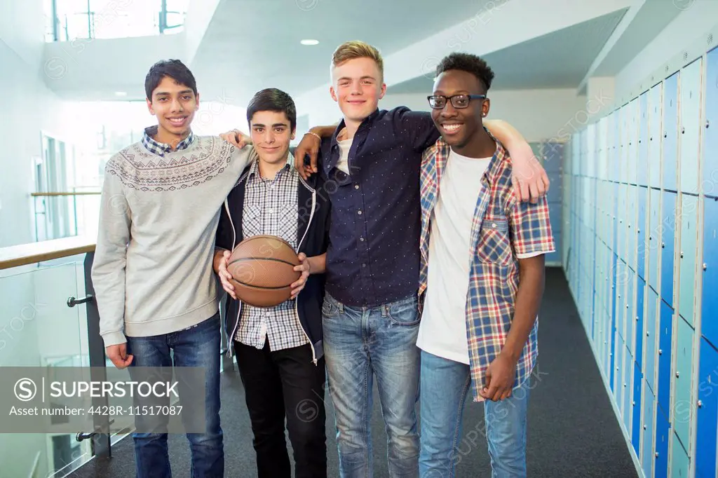 Group portrait of male students holding basketball in school corridor