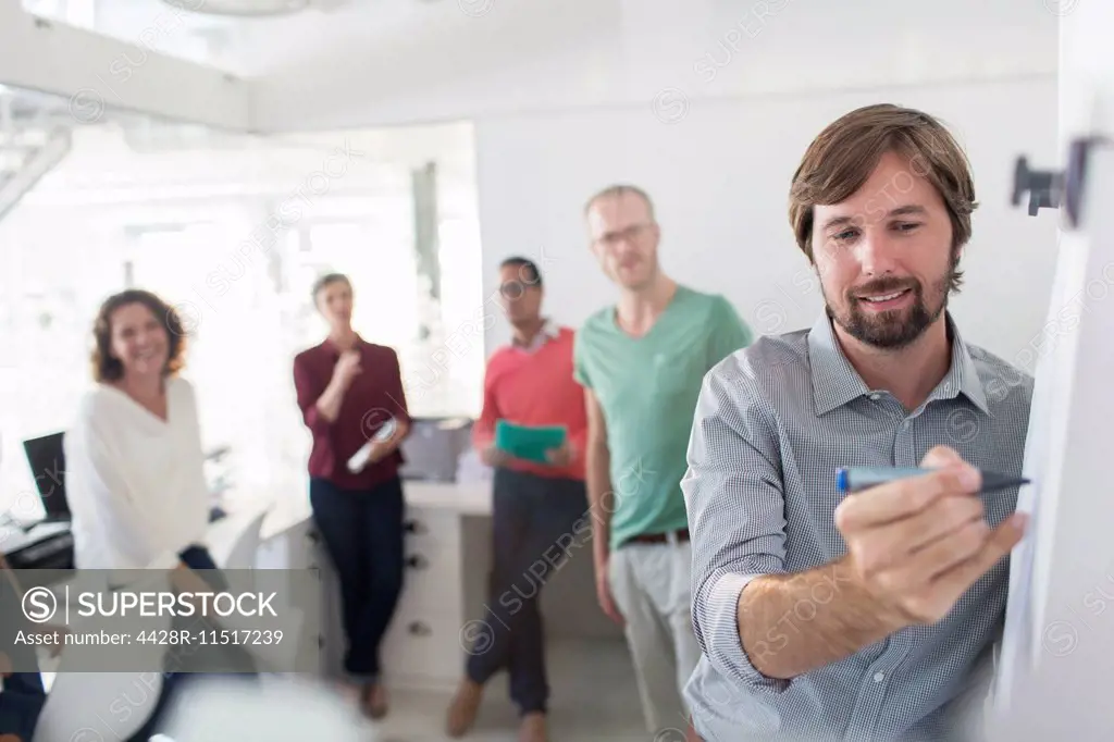 Group of people having meeting in office, man writing on flipchart