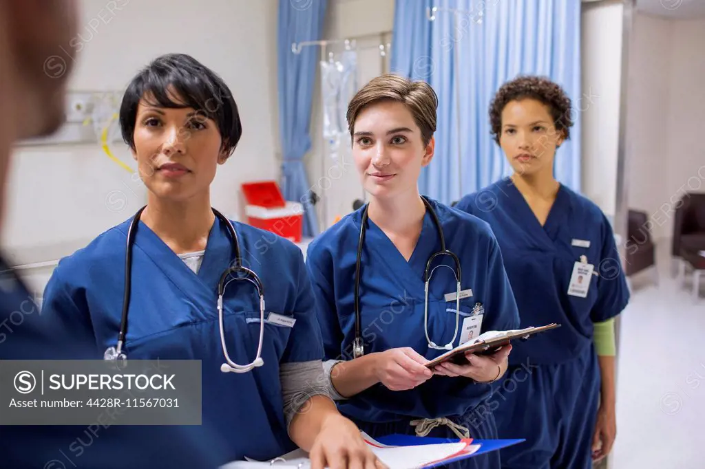 Team of female doctors wearing scrubs talking in hospital ward