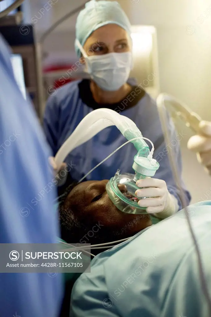 Anesthesiologist holding oxygen mask over patient during surgery