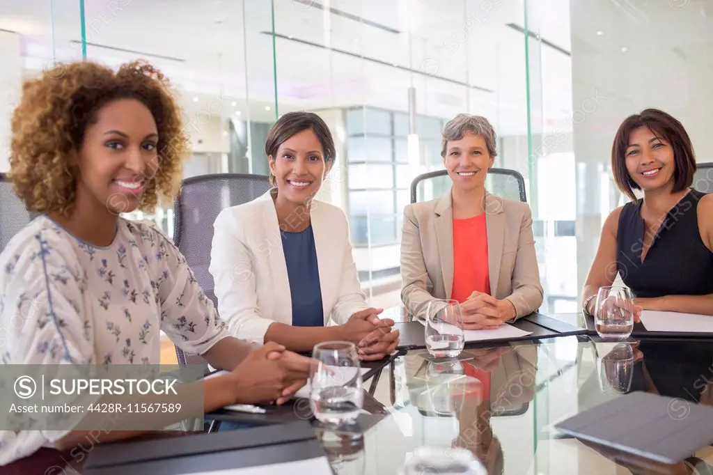 Portrait of four cheerful women sitting at conference table