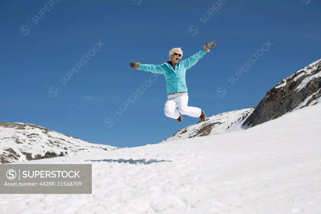 Exuberant woman jumping in snow