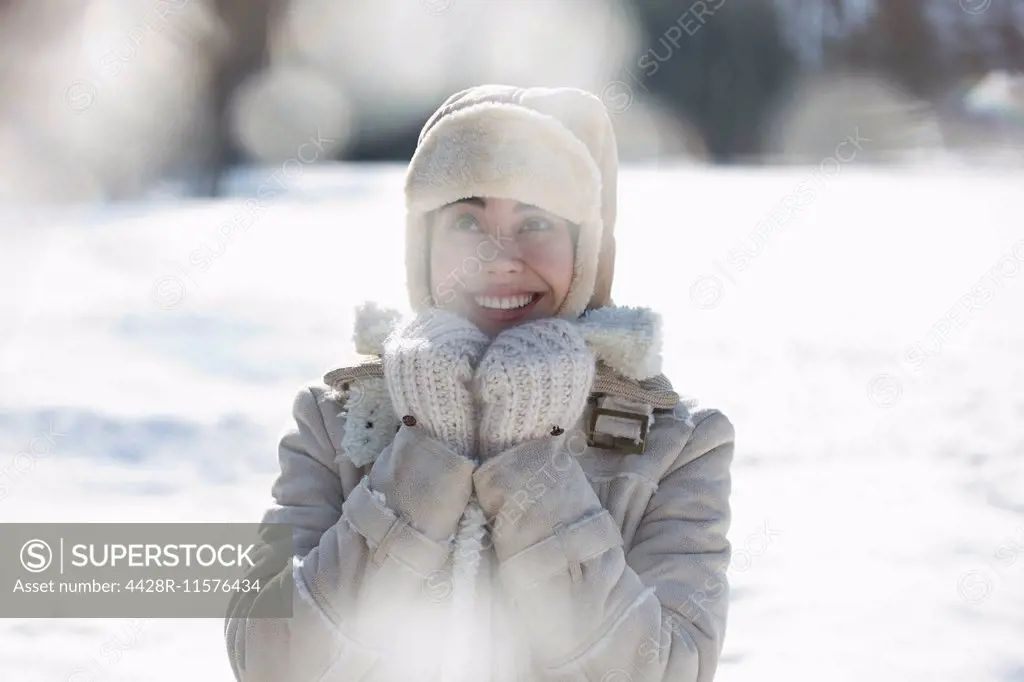 Woman in warm clothing smiling in snow