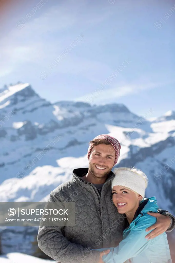Portrait of smiling couple hugging below mountain