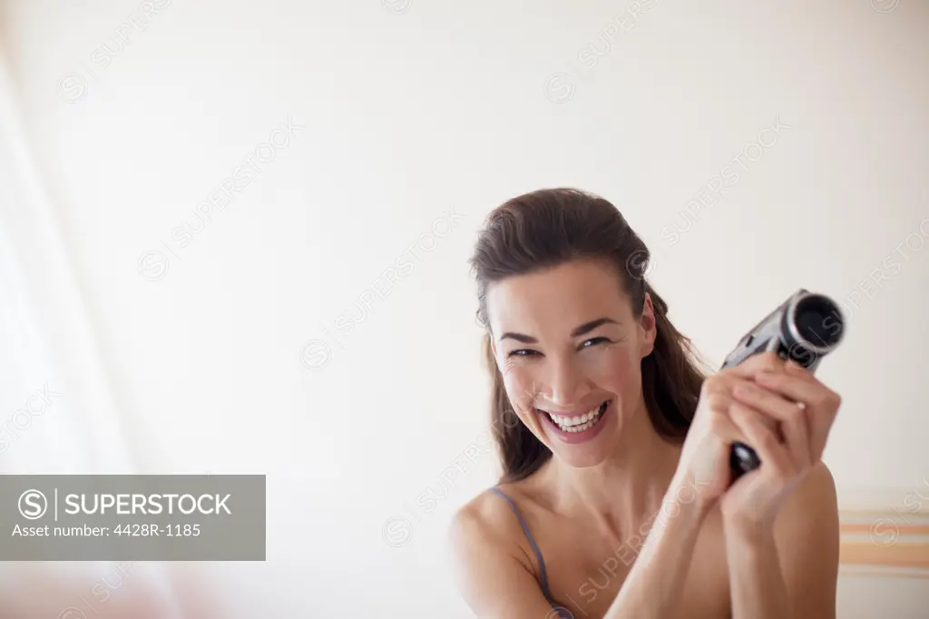 Venice, Portrait of smiling woman with video camera in bedroom