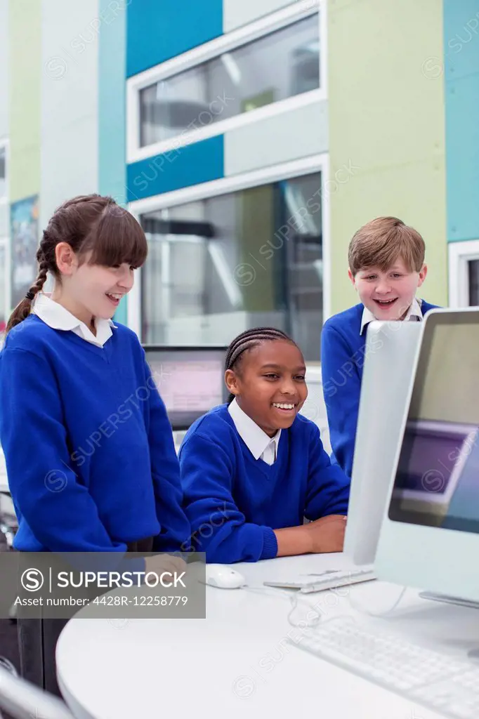 Primary school children looking at computer and smiling
