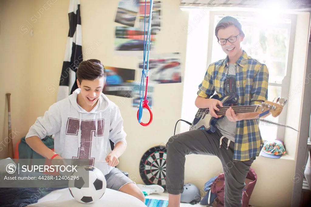 Two teenage boys playing music in room