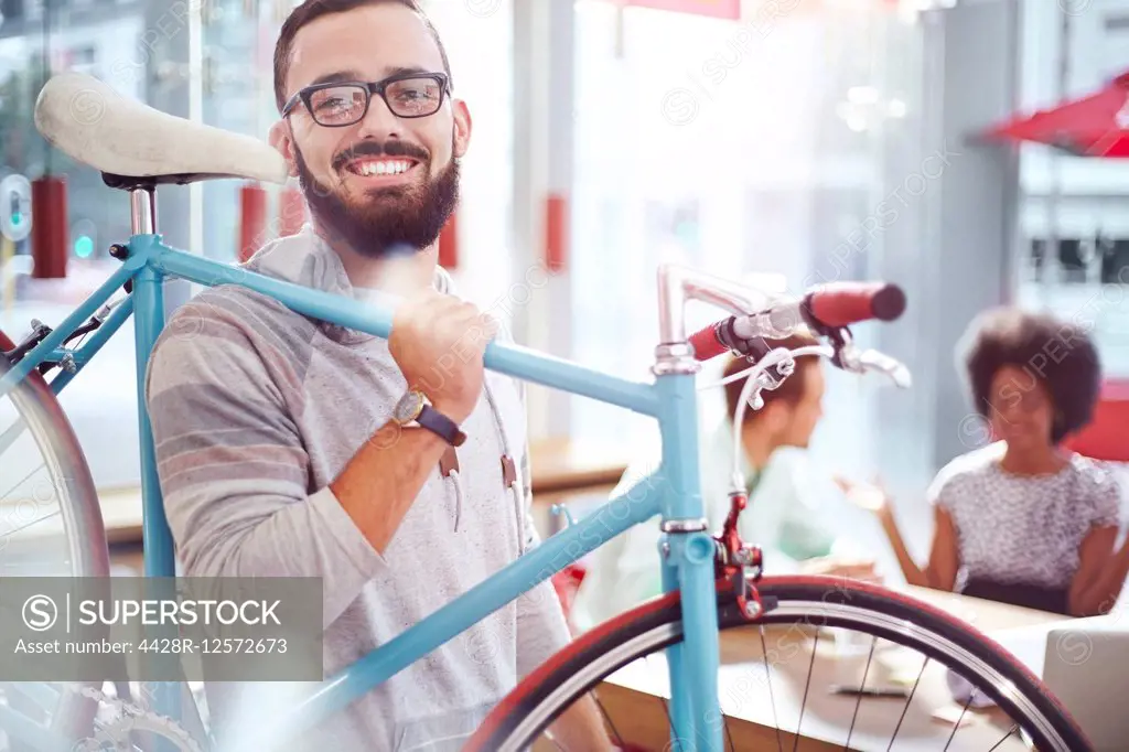 Smiling man carrying bicycle in cafe
