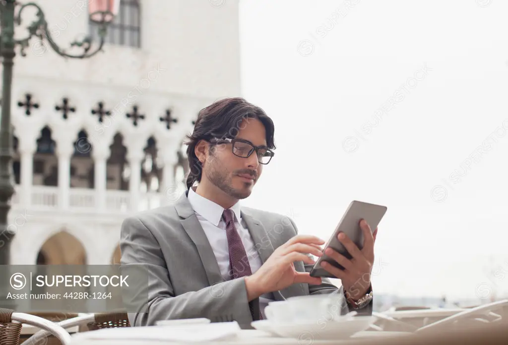 Venice, Businessman using digital tablet at sidewalk cafe in Venice