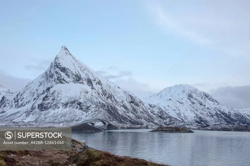 Snow covered mountains along cold lake, Lofoten Islands, Norway