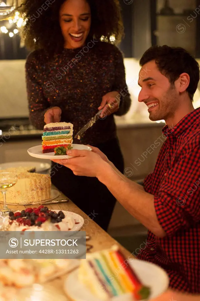 Woman serving layer cake to man at table