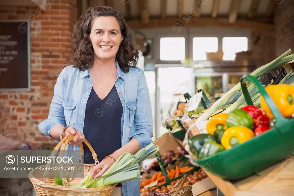 Portrait smiling woman with basket shopping for produce in market