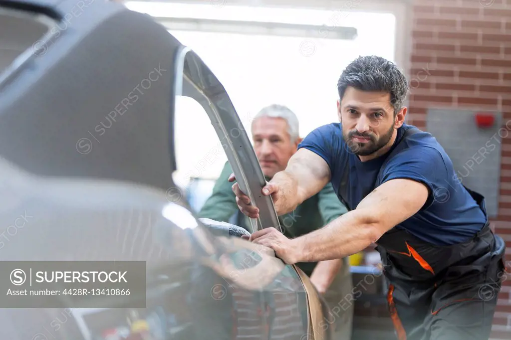 Mechanics pushing car in auto repair shop