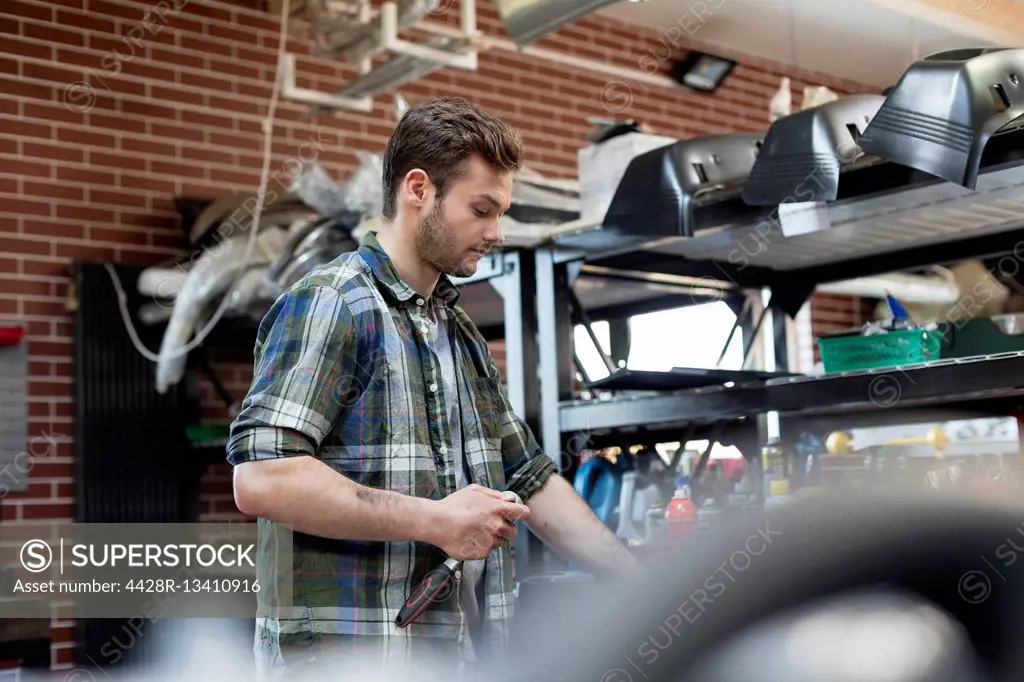 Mechanic holding tool in auto repair shop