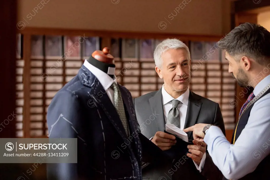 Tailor explaining suit to businessman in menswear shop