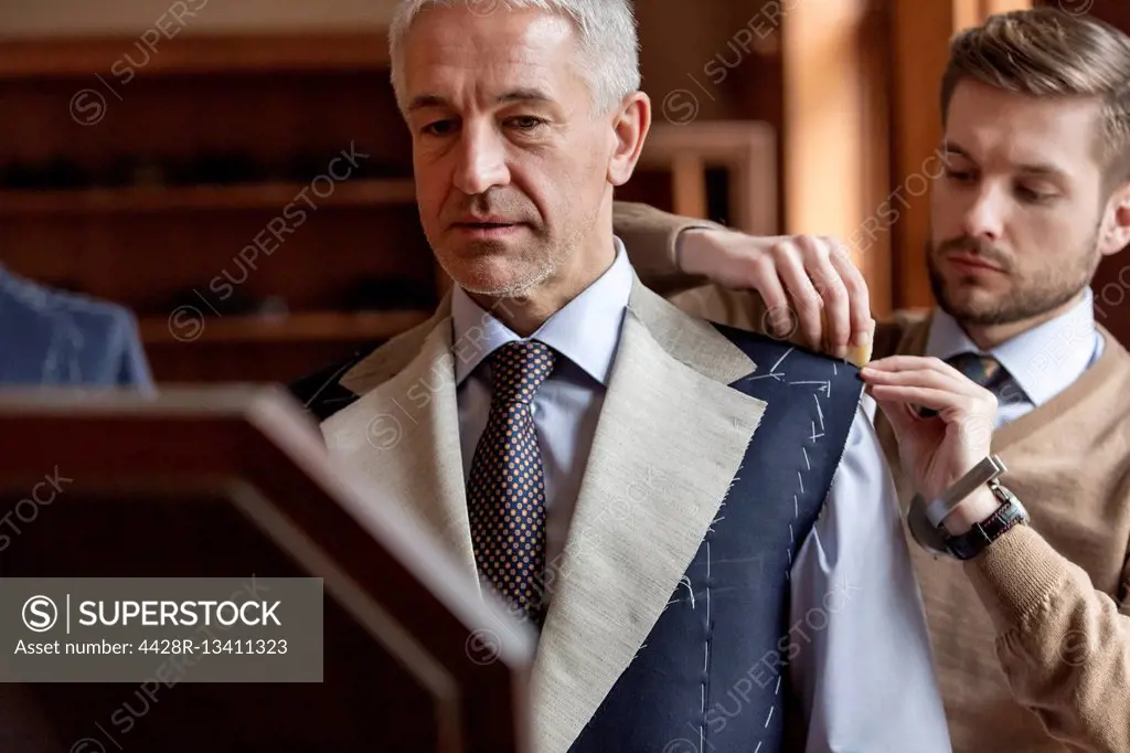 Tailor fitting businessman for suit in menswear shop