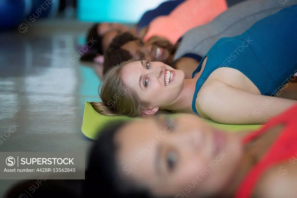 Portrait smiling women practicing bridge pose in yoga class gym studio