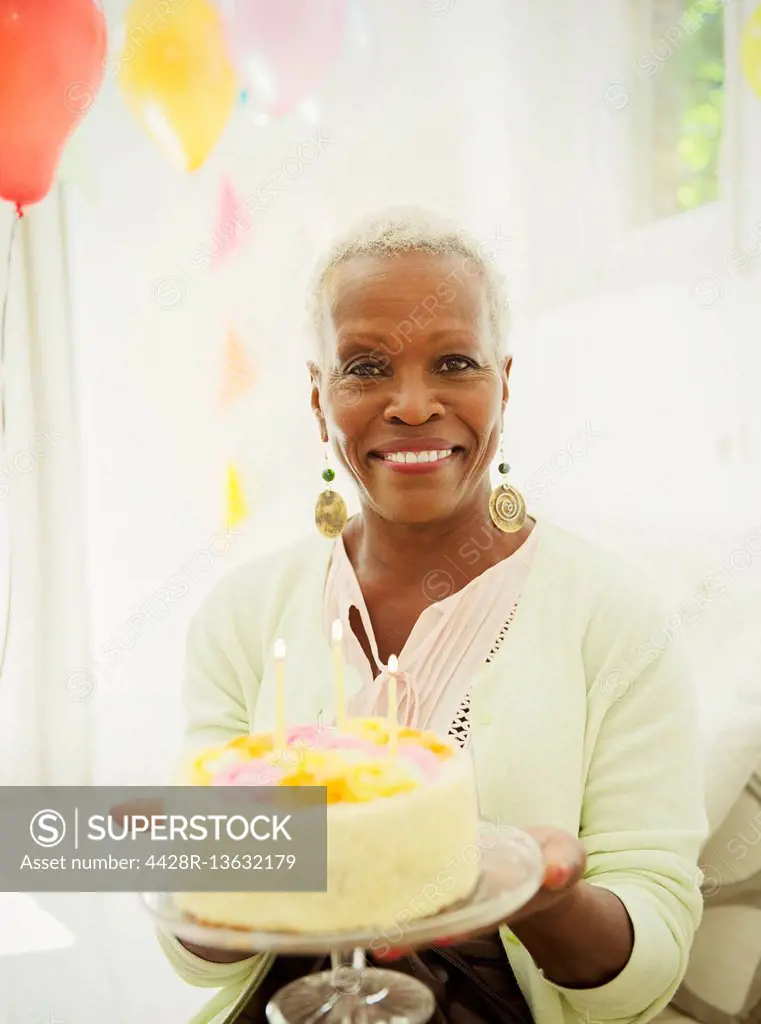 Portrait smiling senior woman holding birthday cake