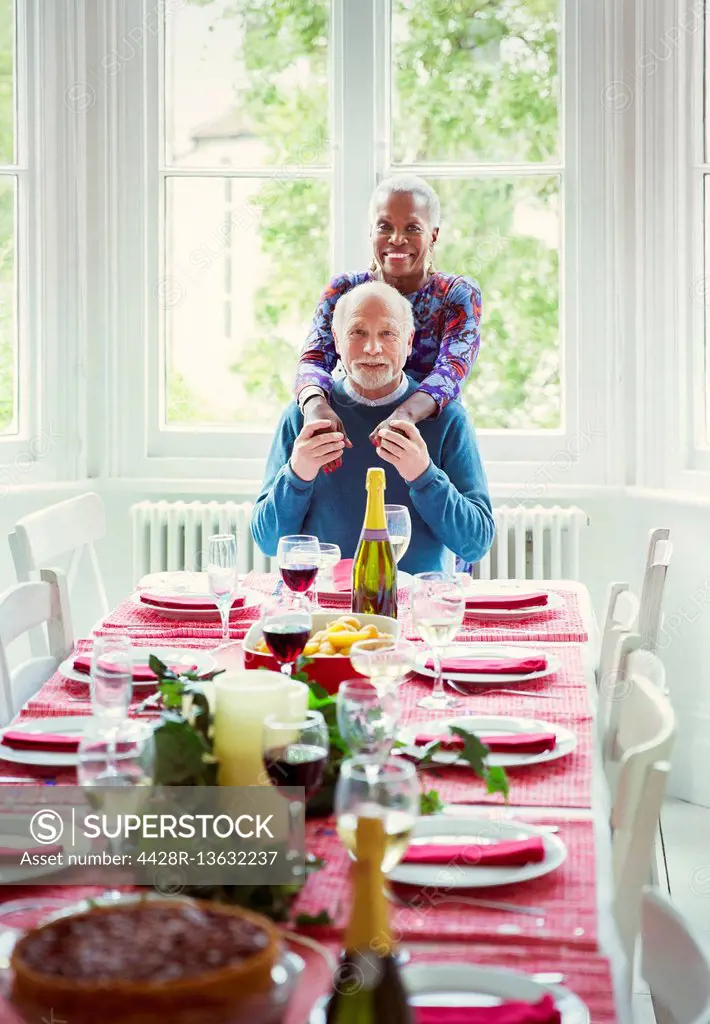 Portrait smiling multi-ethnic senior couple at Christmas dinner table