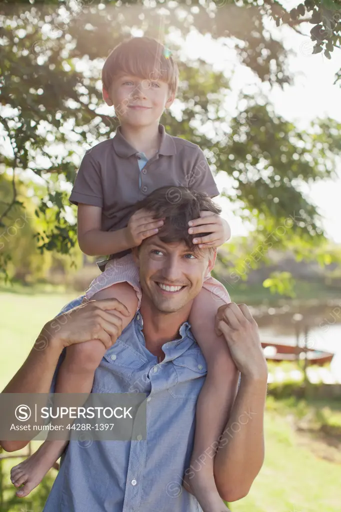 Cape Town, Father carrying smiling son on shoulders at lakeside