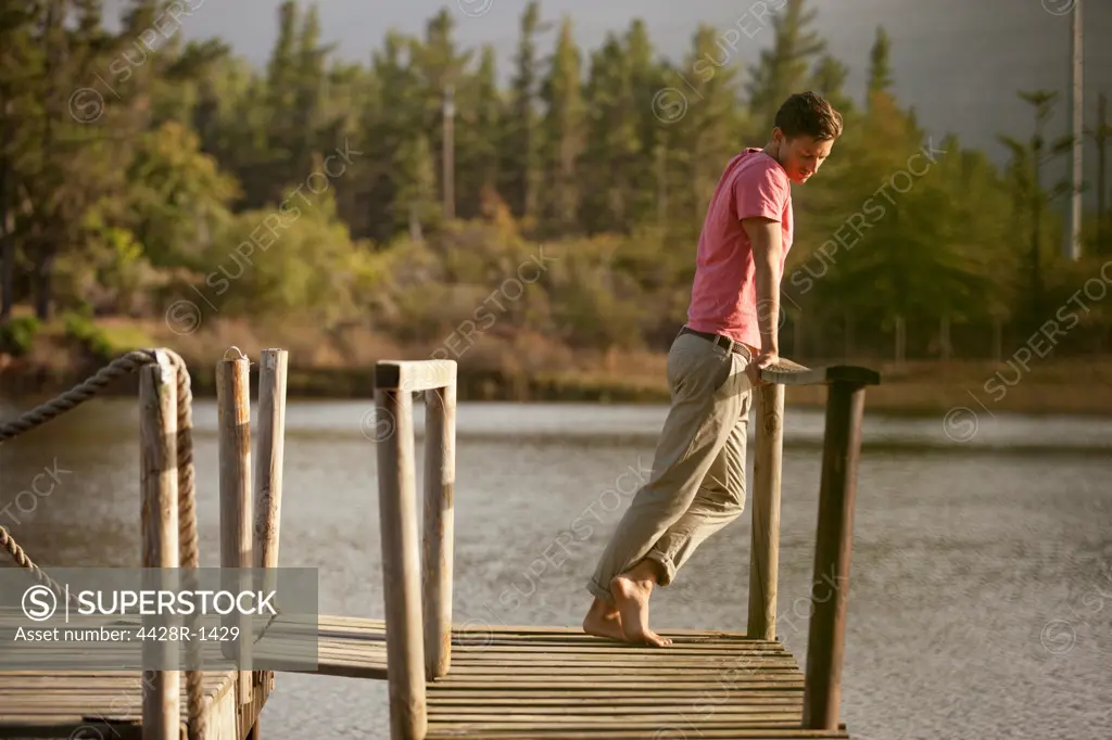 Cape Town, Serene man standing at railing of dock over lake
