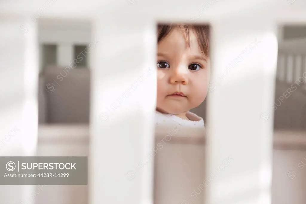 Baby girl sitting up in crib, California, USA