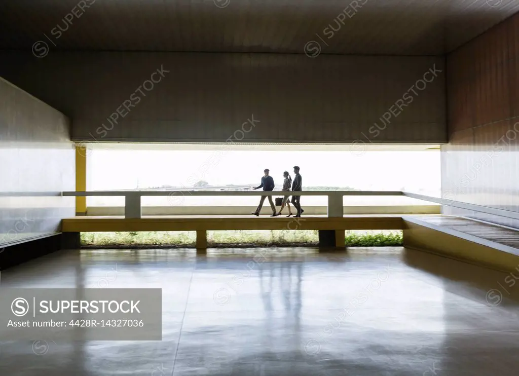Business people walking along elevated walkway in modern office lobby