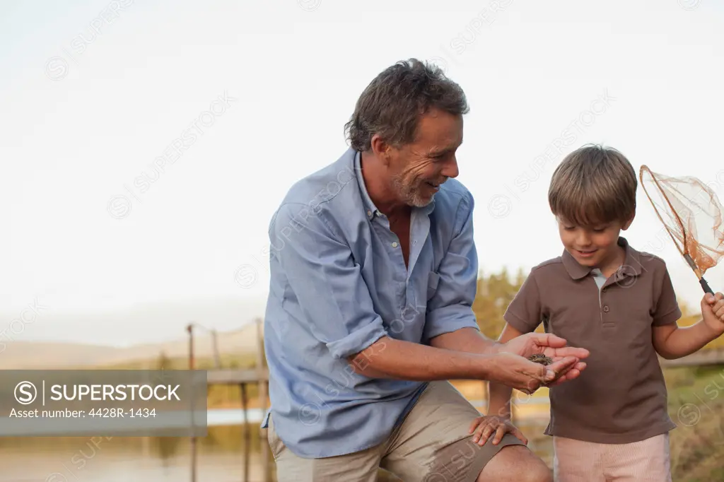 Cape Town, Smiling grandfather and grandson fishing at lakeside