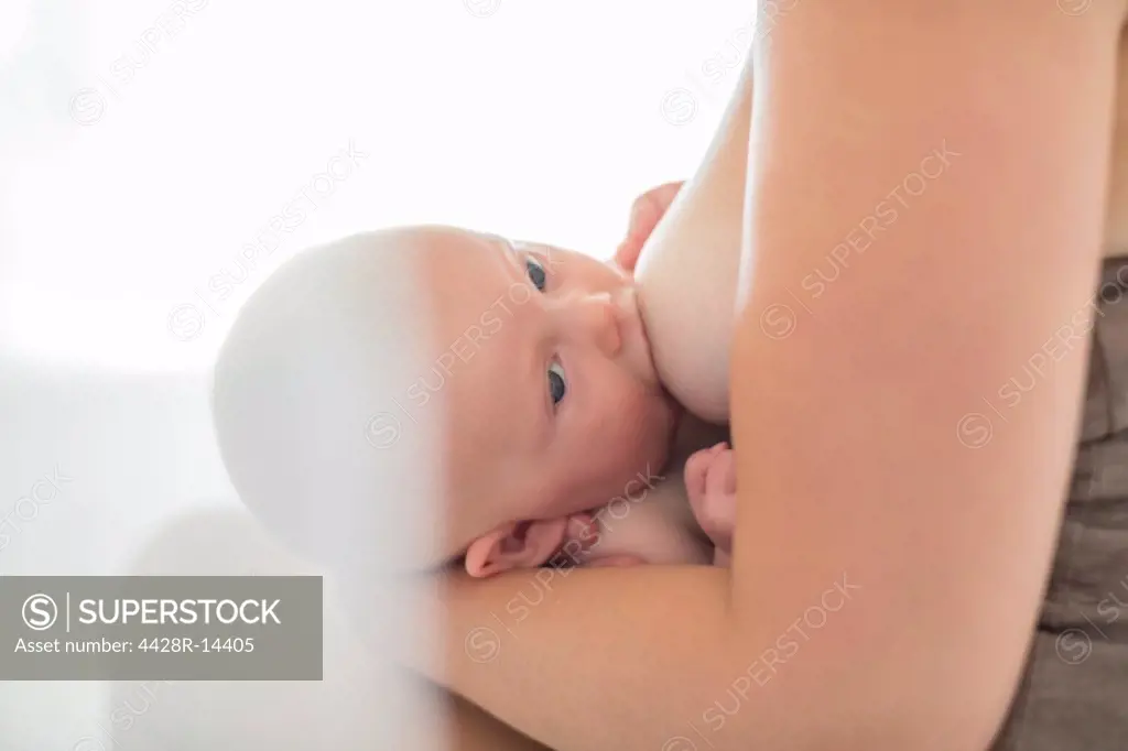 Mother breast-feeding baby girl, London, UK