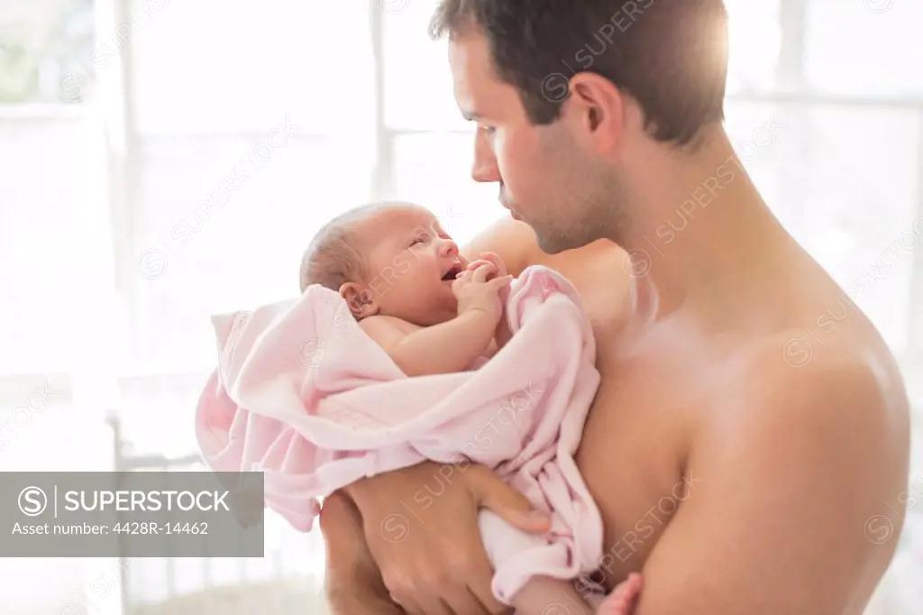 Father holding crying baby girl, London, UK