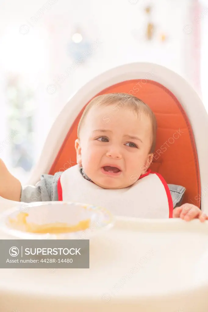 Baby boy crying in high chair, London, UK