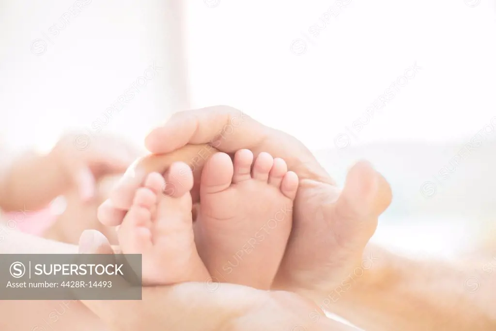 Father cradling baby boy's feet, London, UK