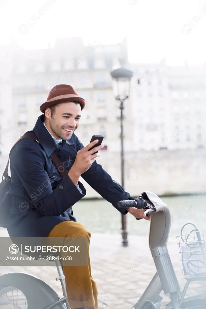 Businessman using cell phone on bicycle along Seine River, Paris, France, Paris, France
