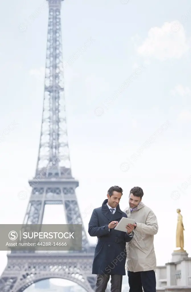 Businessmen using digital tablet by Eiffel Tower, Paris, France, Paris, France