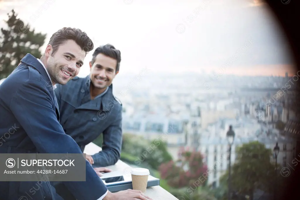Businessmen smiling at railing overlooking Paris, France, Paris, France