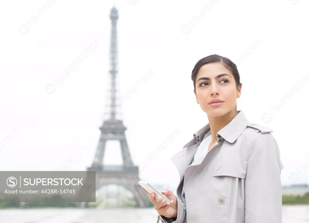 Businesswoman using cell phone near Eiffel Tower, Paris, France, Paris, France