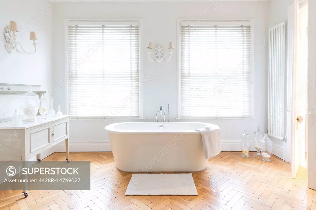 White, luxury home showcase bathroom with soaking tub and parquet hardwood floor