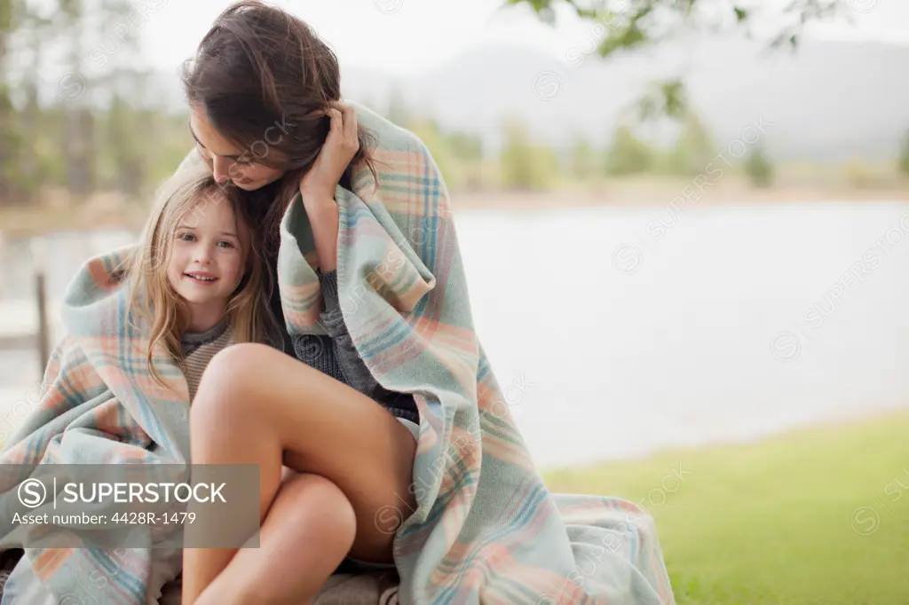 Cape Town, Portrait of smiling daughter wrapped in blanket with mother at lakeside