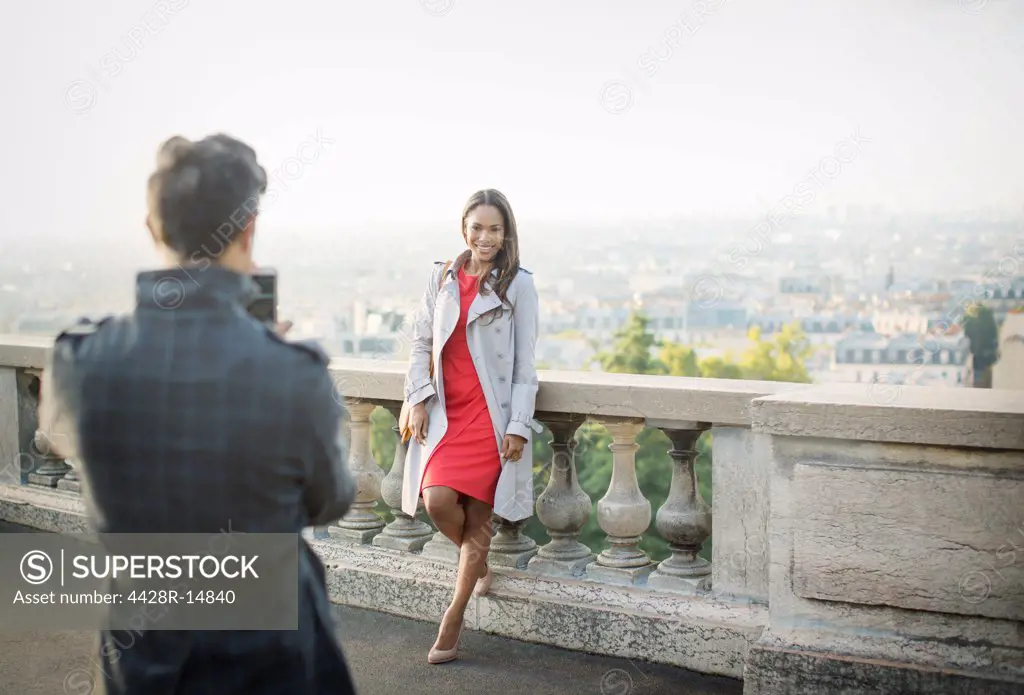 Boyfriend photographing girlfriend with Paris in background, Paris, France