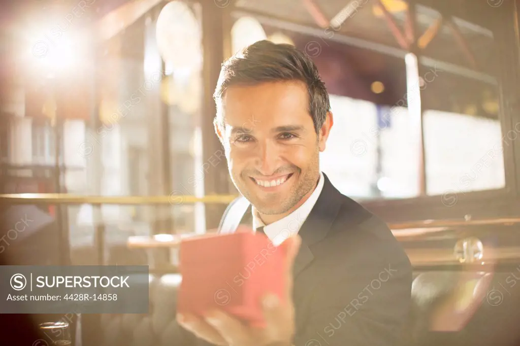 Well-dressed man holding jewelry box in restaurant, Paris, France