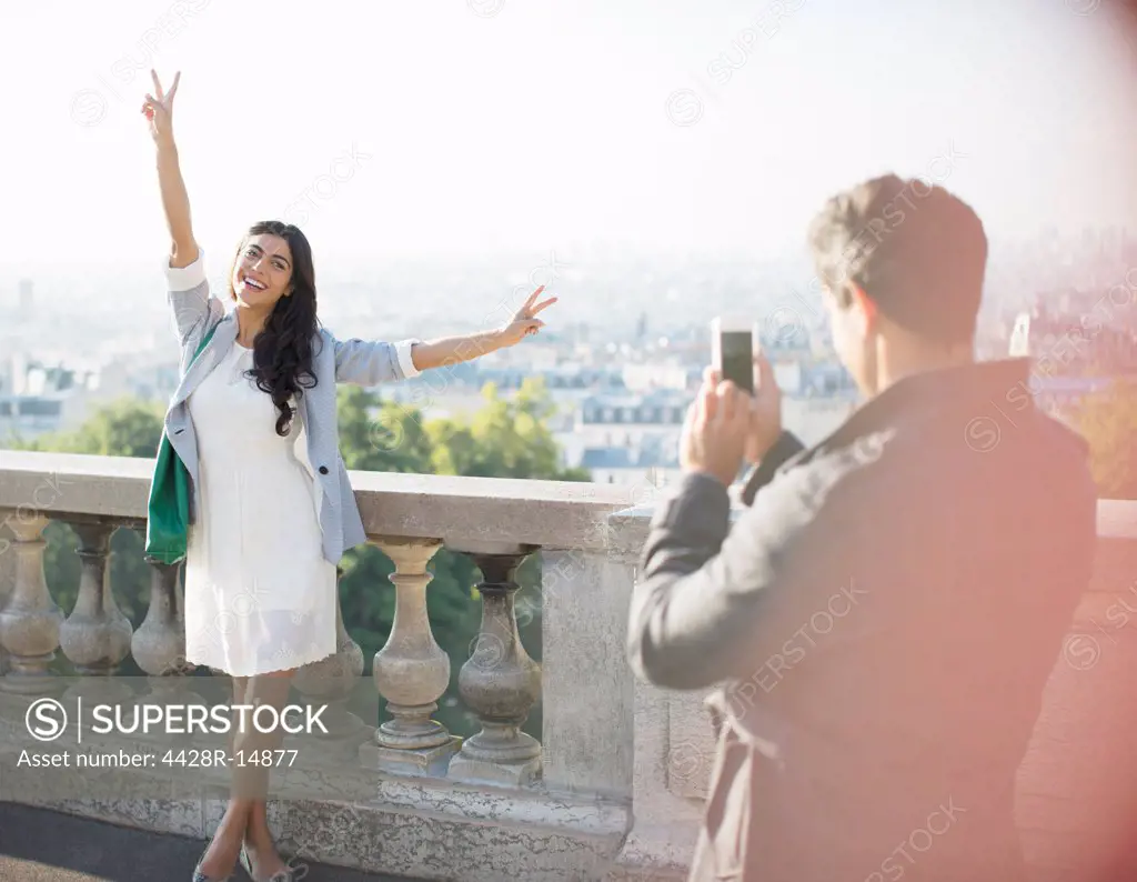 Man photographing girlfriend with city in background, Paris, France
