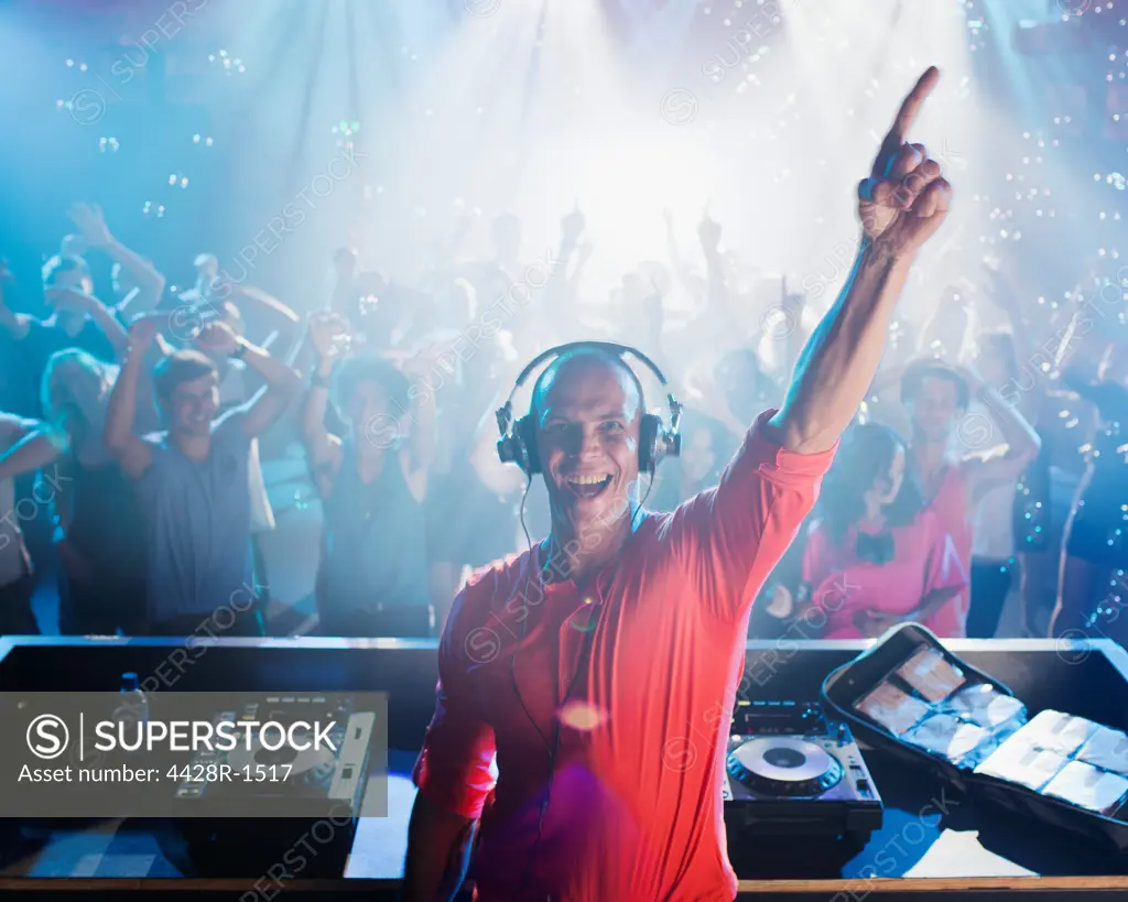 Cape Town, Portrait of enthusiastic DJ with arm raised and people on dance floor in background