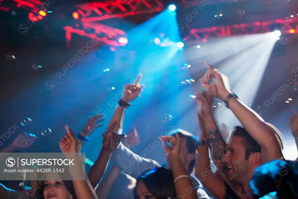 Cape Town, Enthusiastic crowd with arms raised on dance floor of nightclub