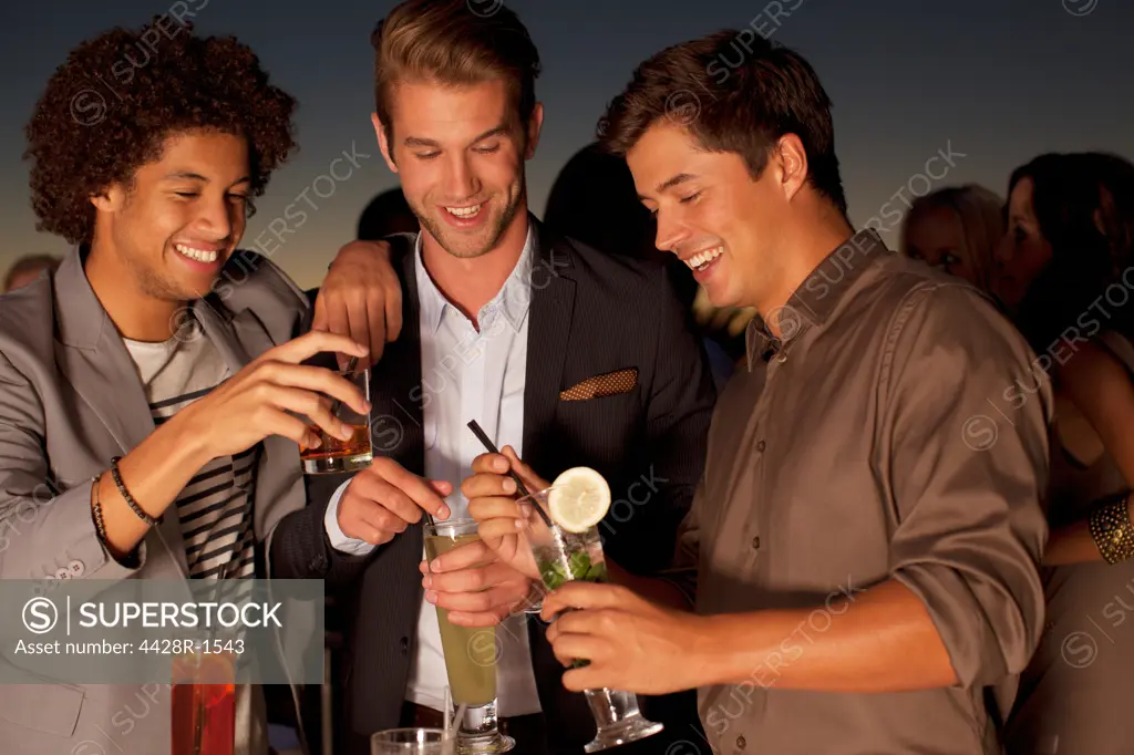 Cape Town, Smiling men toasting cocktails in nightclub