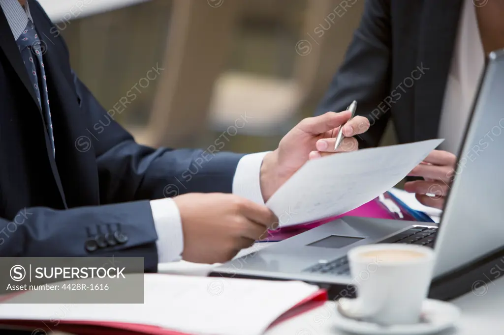 Spain, Close up of business people reviewing paperwork at cafe