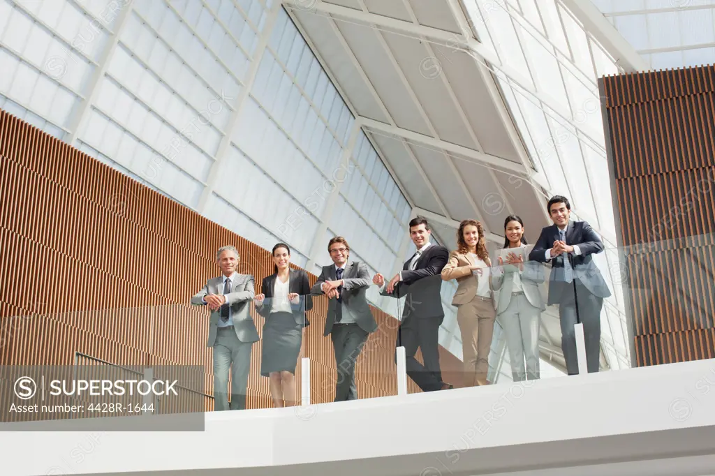Spain, Portrait of smiling business people leaning on balcony railing