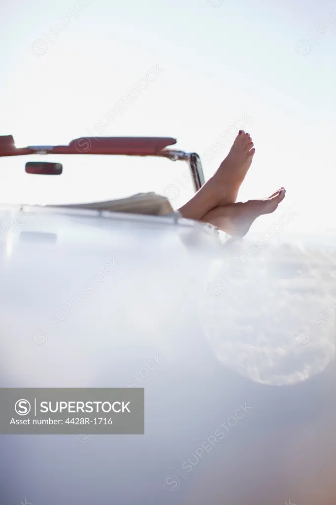 Los Angeles, USA, Womans feet resting on convertible